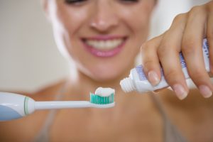 Closeup on hands squeezing toothpaste on electric toothbrush
